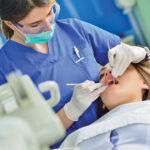 A dental student performs a checkup on a patient.