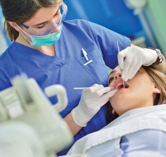 A dental student performs a checkup on a patient.