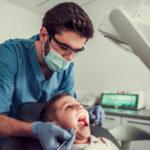 A dentist checks a child's teeth from above.