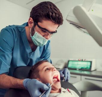 A dentist checks a child's teeth from above.