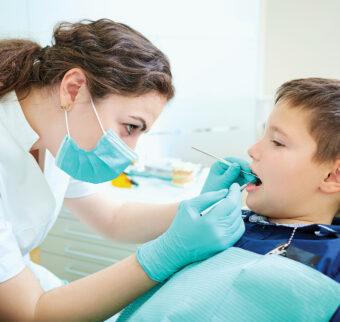 A female dentist performs a checkup on a child patient.