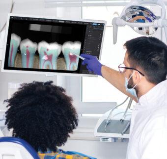 A dentist talks a patient through an AI image of their dental issue.