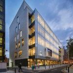 A modern building on the RCSI campus pictured all lit up at night.