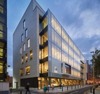 A modern building on the RCSI campus pictured all lit up at night.